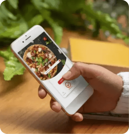 Person browsing a food product catalog on a mobile phone, with fresh ingredients in the background